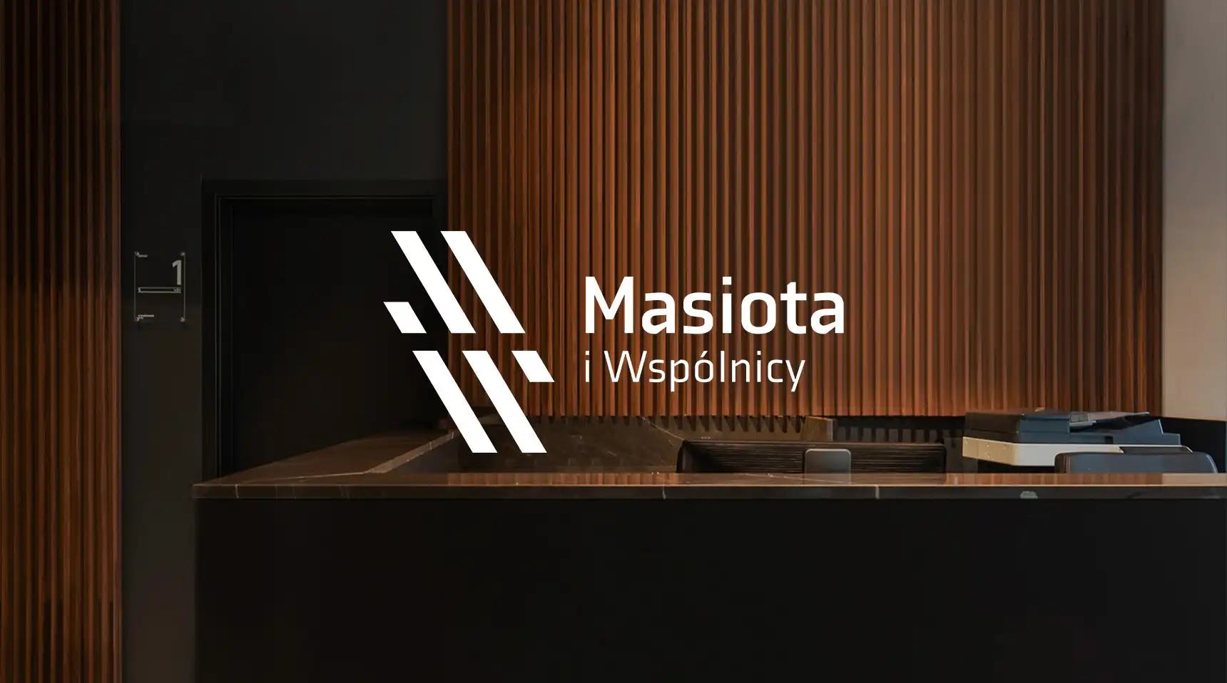 Obraz przedstawia logo na tle recepcji biura Masiota i Wspólnicy