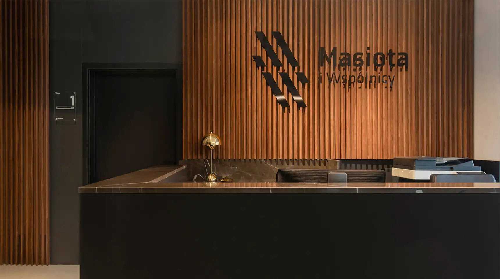 Obraz przedstawia recepcję biura z logo na ścianie Masiota i Wspólnicy
